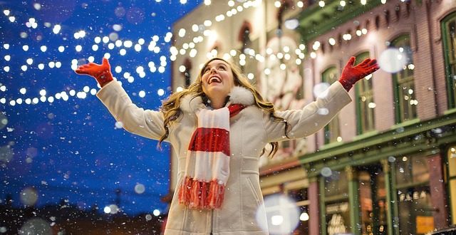 Une jeune femme s'extasie sous les décorations de Noël et la neige.