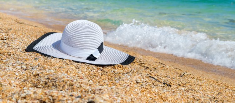 C'est une plage et au bord de l'eau de sable, il y a un chapeau blanc.