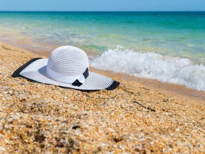 C'est une plage et au bord de l'eau de sable, il y a un chapeau blanc.