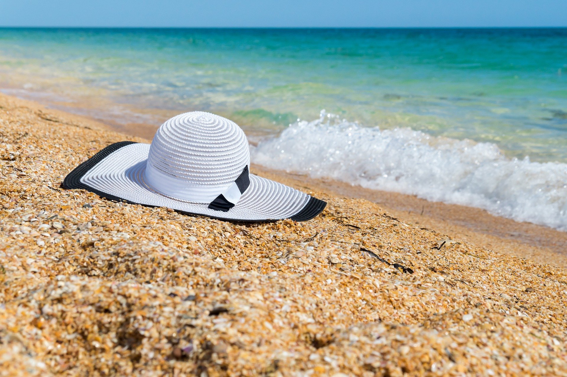 C'est une plage et au bord de l'eau de sable, il y a un chapeau blanc.